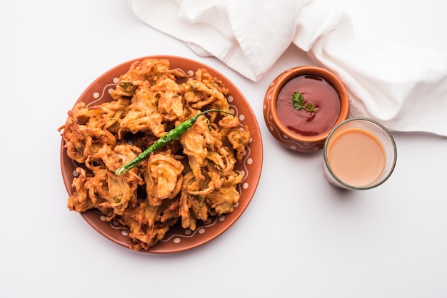 Fried Onion Pakora oder Pyaj Pakoda, auch bekannt als Crispy Kanda Bhaji / Bhajji / Bajji, beliebter indischer Snack zur Teezeit während der Regenzeit. serviert mit Tomatenketchup
