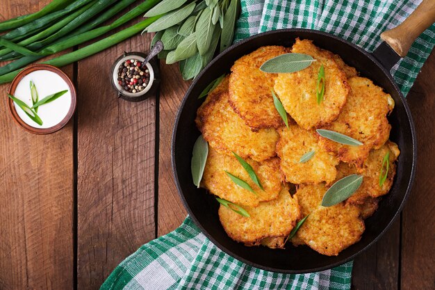 Fried panqueques de patata en una sartén en una mesa de madera