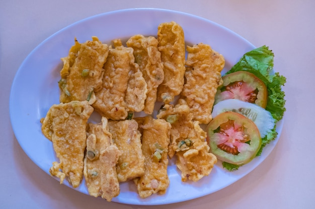 Foto fried tempeh oder tempe goreng ist ein traditionelles indonesisches essen, das aus fermentierter sojabohne auf einer weißen platte hergestellt wird.