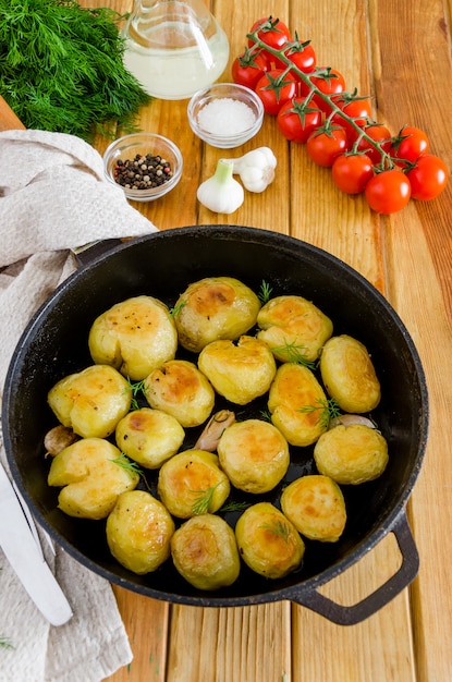 Fried Young Potatoes en una sartén de hierro fundido con ajo y eneldo. Estilo rústico