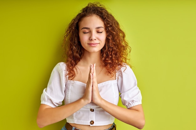 Friedlicher Geist. Porträt des Mädchens, das mit namaste Geste auf Grün meditiert