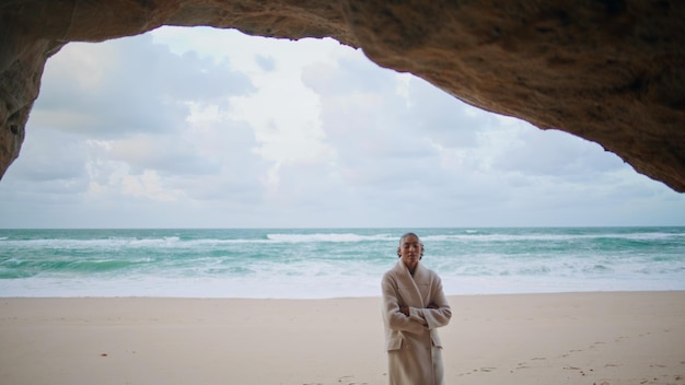 Friedlicher Reisender erkundet das Meer, spaziert am Strand, lockerte Frau versteckt sich in der Ozeanhöhle.