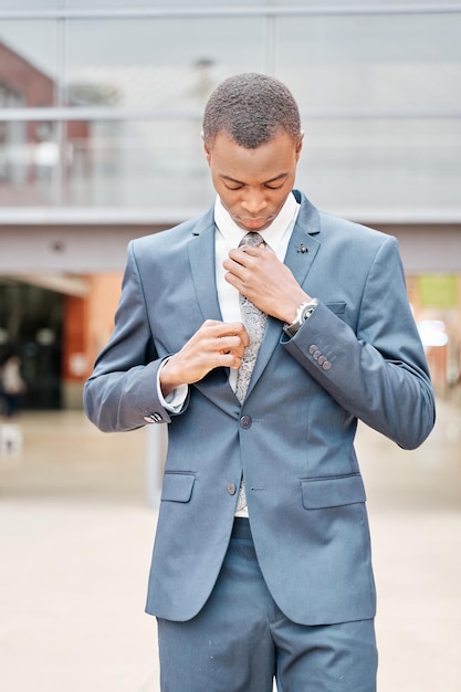 Friedliches afrikanisch-amerikanisches Geschäftsmannporträt eines erfolgreichen Mannes im Anzug außerhalb des Bürogebäudes, der seine Krawatte zuknöpft