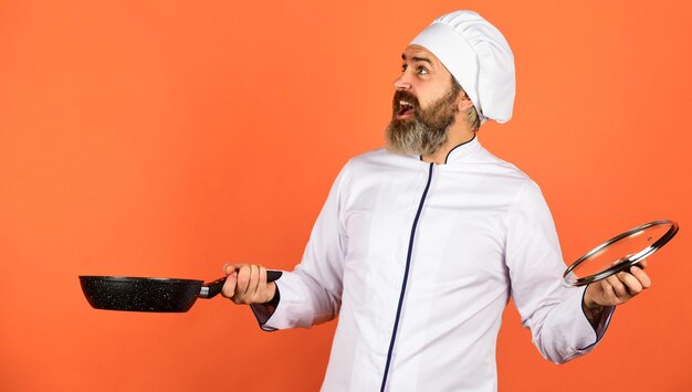 Frigideira de alta qualidade. Homem barbudo cozinheiro uniforme branco. Cozinhando como profissional. Cozinhar regularmente. Refeição saborosa fácil preparada em casa. Café da manhã caseiro. Preparar comida na cozinha. Cozinhar o conceito de comida.