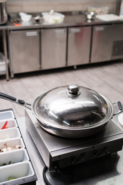 Frigideira e outros utensílios de cozinha em restaurante profissional. Ajudantes do Chef