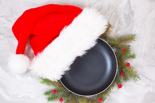 Frigideira ou frigideira com chapéu de Natal na mesa de mármore na mesa de mármore. Vista do topo.