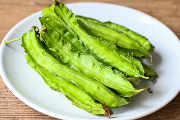 Frijol alado sobre fondo de placa blanca Psophocarpus tetragonolobus Frijoles alados verdes o de cuatro ángulos