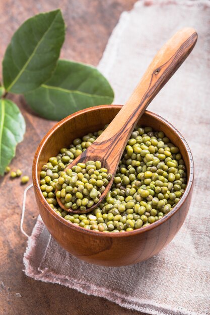 Frijol mungo verde en un recipiente en la mesa de madera