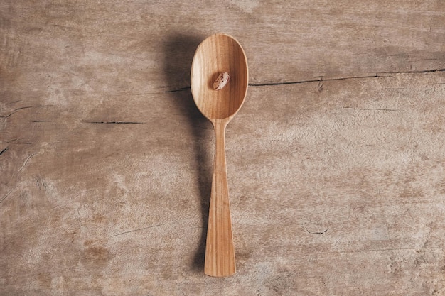 Frijol seco crudo en una cuchara de madera sobre un fondo de madera. Vista superior. Copiar, espacio vacío para texto