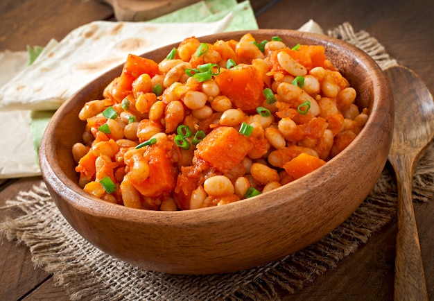 Frijoles blancos guisados y rodajas de calabaza en salsa de tomate