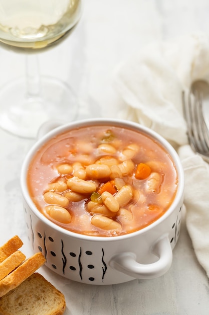 Frijoles blancos hervidos con verduras y salsa en un tazón blanco