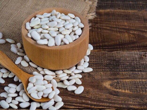 Foto frijoles blancos en un recipiente de madera sobre una mesa de madera antigua, legumbres, espacio de copia