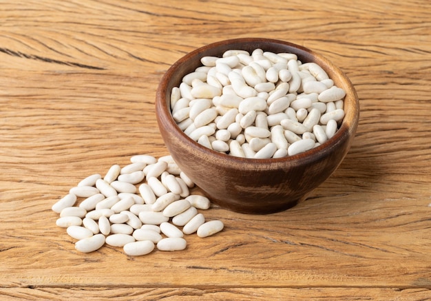 Frijoles blancos en un recipiente sobre una mesa de madera