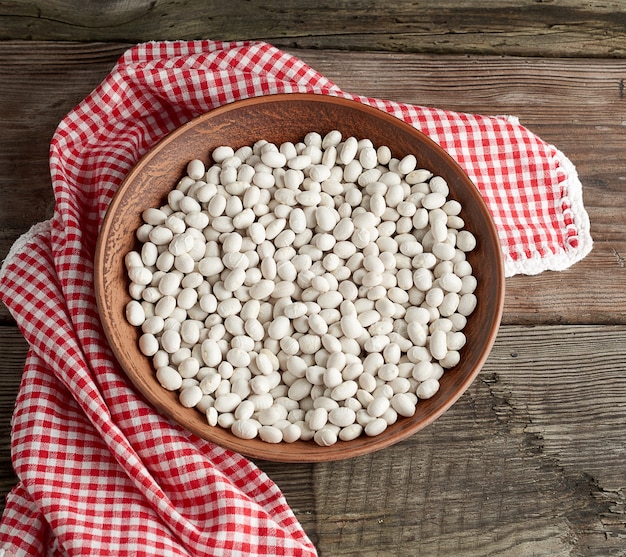 Foto frijoles blancos redondos crudos en un plato sobre una mesa de madera