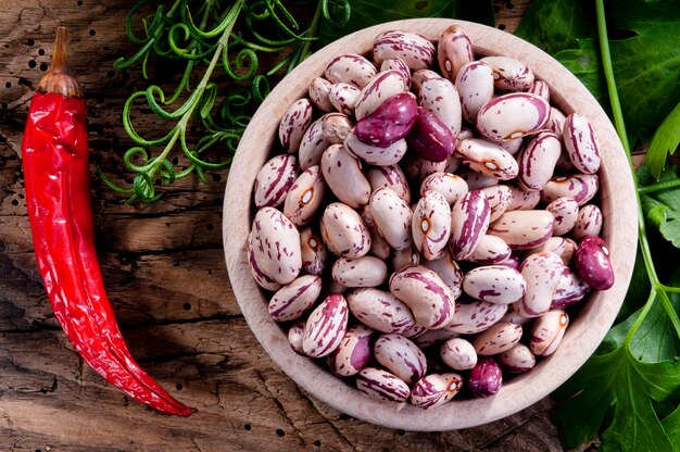 Frijoles crudos y chile en una tabla de madera