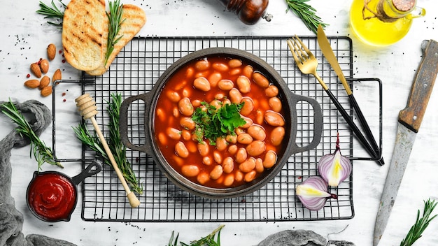 Frijoles hervidos en salsa de tomate con perejil y especias en una sartén de metal negro Estilo rústico Vista superior