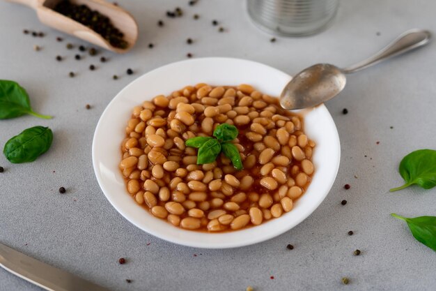 Foto frijoles horneados en salsa de tomate en un plato contra un fondo gris comida fondo de comida primer plano