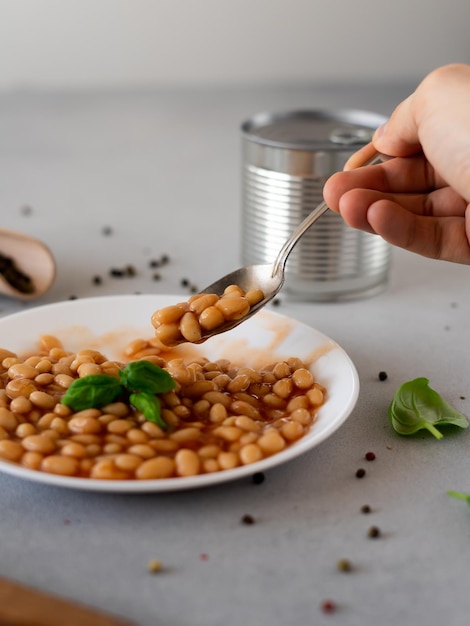 Frijoles horneados en salsa de tomate en un plato contra un fondo gris Comida Fondo de comida Primer plano