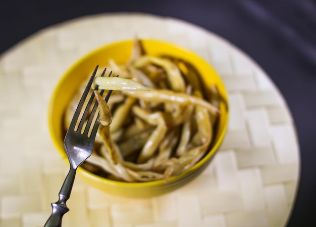 Frijoles largos fritos en taza de cerámica amarilla.