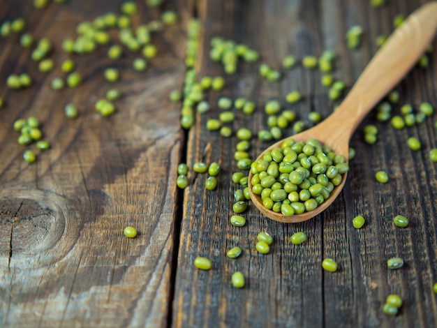 Frijoles mungo verdes crudos en un tazón sobre una vieja planta leguminosa de mesa de madera para una dieta saludable