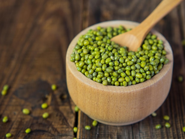 Frijoles mungo verdes crudos en un tazón sobre una vieja planta leguminosa de mesa de madera para una dieta saludable