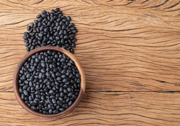 Frijoles negros en un bol sobre una mesa de madera con espacio para copiar