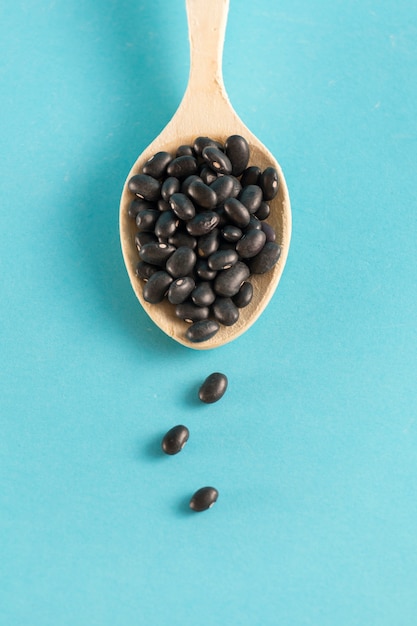 Foto frijoles negros en una cuchara de madera