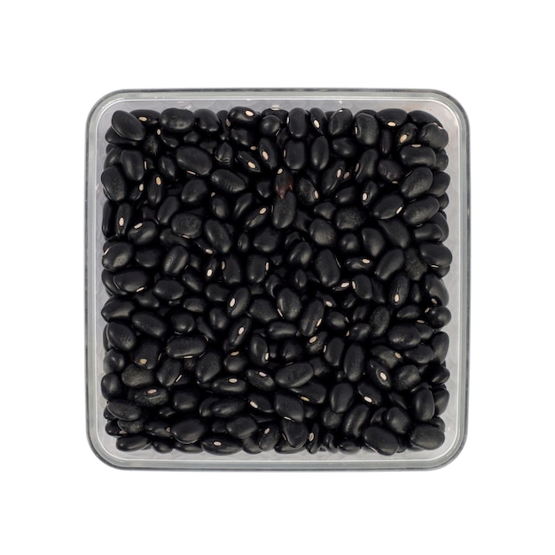 Frijoles negros en una olla transparente sobre fondo blanco.