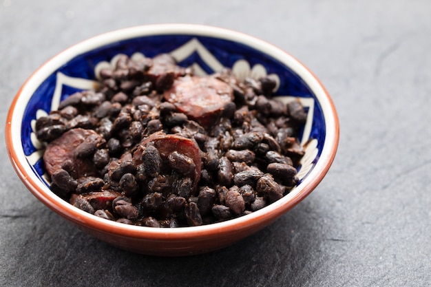 Frijoles negros con salchichas ahumadas en plato de cerámica