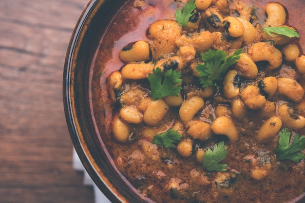 Frijoles de ojos negros al curry o chawli o chavli chi usal o masala, servido en un cuenco de cerámica sobre fondo cambiante, enfoque selectivo