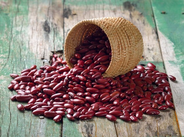 Frijoles rojos en la cesta en la mesa de madera vieja