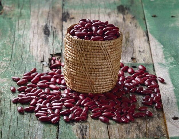 Frijoles rojos en la cesta en la mesa de madera vieja