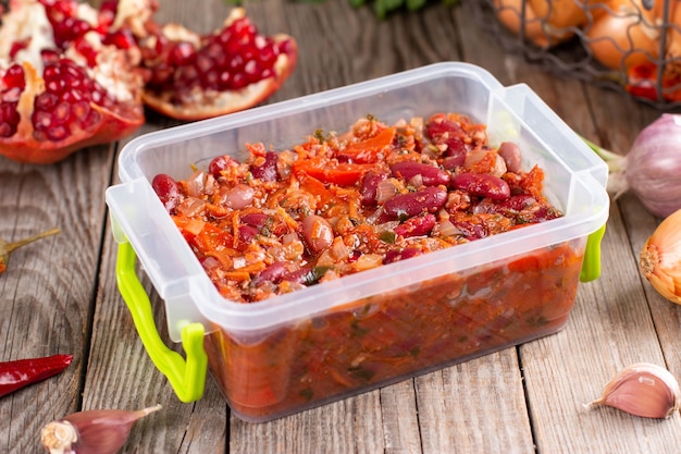 Frijoles rojos guisados congelados en salsa de tomate en un recipiente sobre la mesa de madera