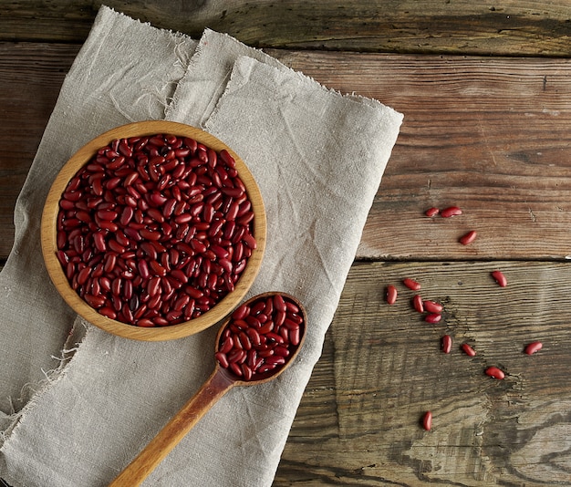 Frijoles rojos ovales crudos en un plato sobre una mesa de madera. Comida orgánica