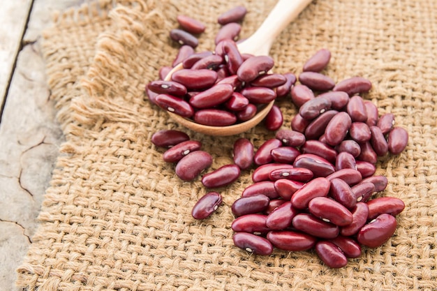 Frijoles rojos en saco de arpillera sobre fondo de madera