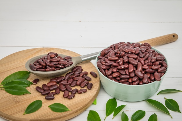 Foto frijoles rojos en el tazón y cuchara en la mesa blanca.