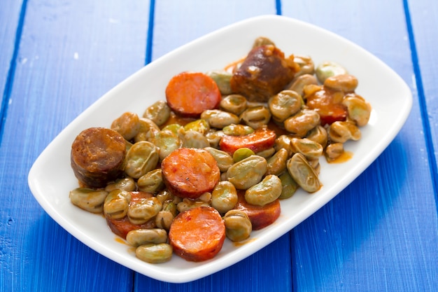 Frijoles con salchichas ahumadas en plato blanco