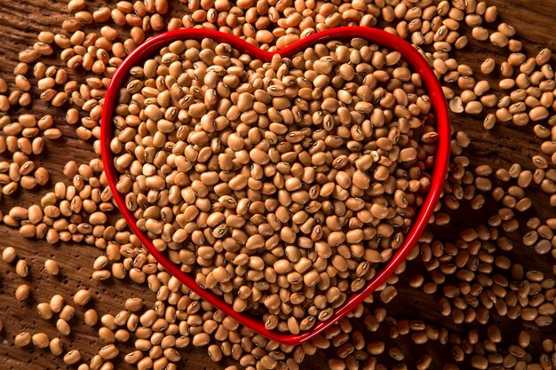 Frijoles en un tazón de corazón sobre la mesa de madera