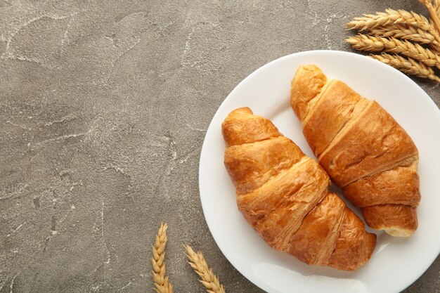 Frisch Croissant mit Weizen auf grauem Hintergrund. Ansicht von oben