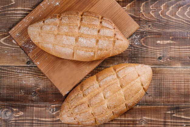 Frisch gebackene Brotlaibe auf dem hölzernen Hintergrund