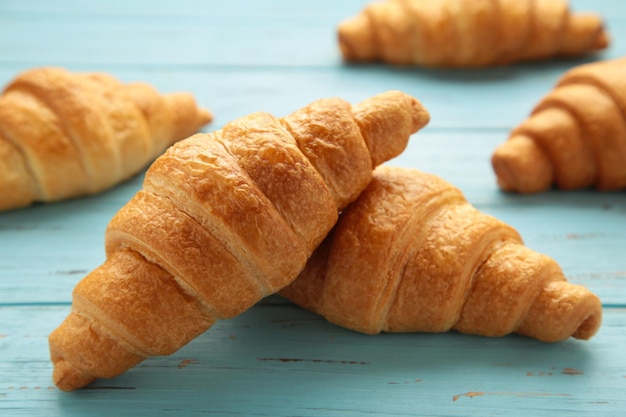 Frisch gebackene Croissants auf blauem Holzhintergrund Warme, frische Buttercroissants und Brötchen Französische und amerikanische Croissants und gebackenes Gebäck