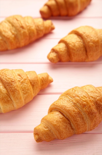 Frisch gebackene Croissants auf rosafarbenem Holzhintergrund Warme frische Buttercroissants und Brötchen Französische und amerikanische Croissants und gebackenes Gebäck