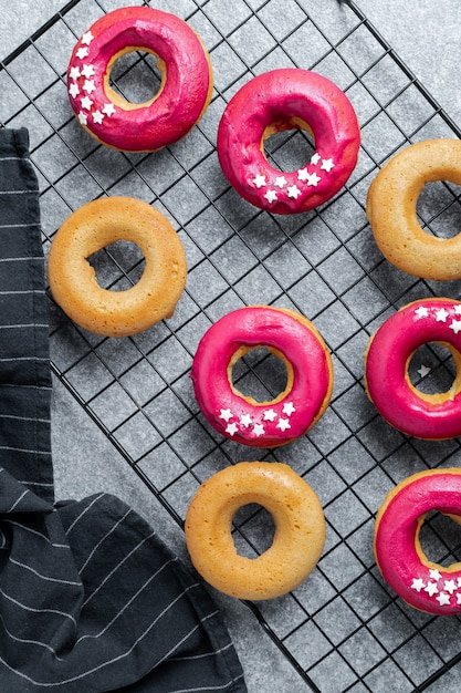 frisch gebackene Donuts mit leuchtend rosa Zuckerguss auf Kühlregal