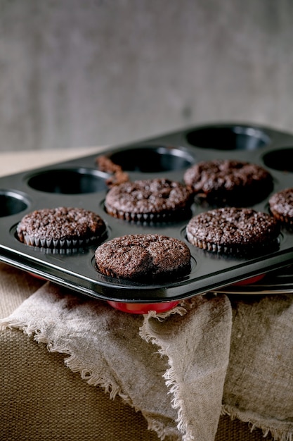 Frisch gebackene hausgemachte Schokoladencupcakes Muffins in Form zum Kochen stehend auf Küchentisch mit Tischdecke. Hausbäckerei