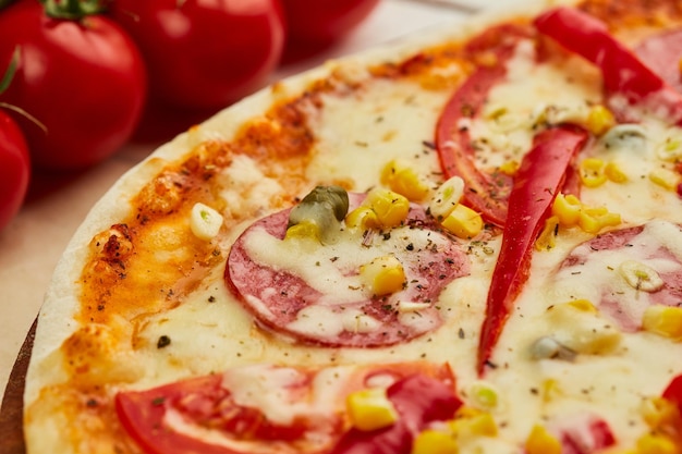 Frisch gebackene leckere Peperoni-Pizza mit Salami-Mozzarella-Käse, Mais und Pfeffer, serviert auf Holzhintergrund mit Tomatensoße und Kräutern Konzept der Lebensmittellieferung Restaurantmenü