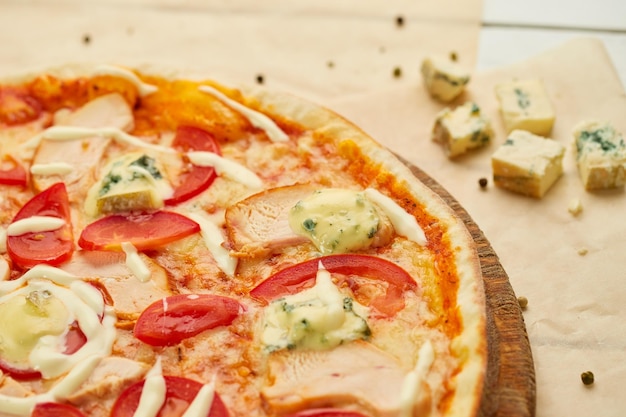 Frisch gebackene Pizza mit geräuchertem Hähnchenfilet und Gorgonzola-Käse, serviert auf Holzhintergrund mit Tomatensoße und Kräutern Food-Delivery-Konzept Restaurantmenü