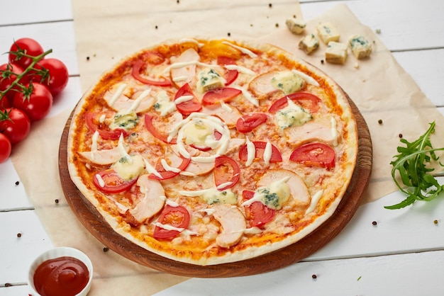 Frisch gebackene Pizza mit geräuchertem Hähnchenfilet und Gorgonzola-Käse, serviert auf Holzhintergrund mit Tomatensoße und Kräutern Food-Delivery-Konzept Restaurantmenü
