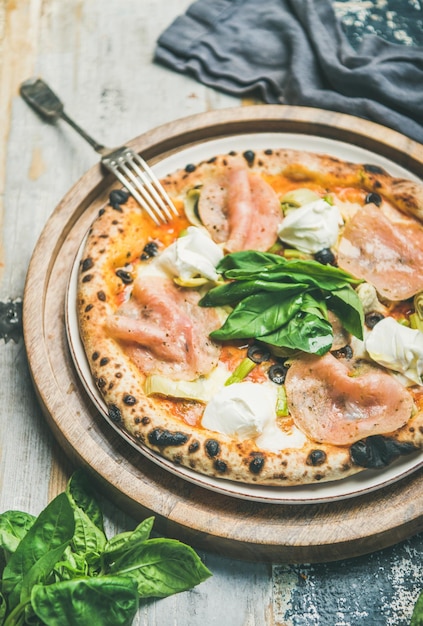 Frisch gebackene Pizza mit Schinken, Artischocken und Frischkäse