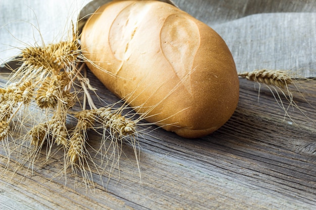 Frisch gebackene Stangenbrote Brot- und Weizenspitzen auf hölzernem Hintergrund