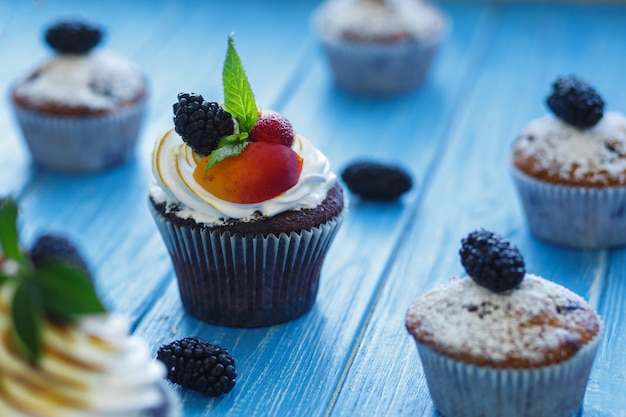 Frisch gebackene süße Muffins auf blauer Oberfläche. Süßes Gebäck, Rezepte, Kochen